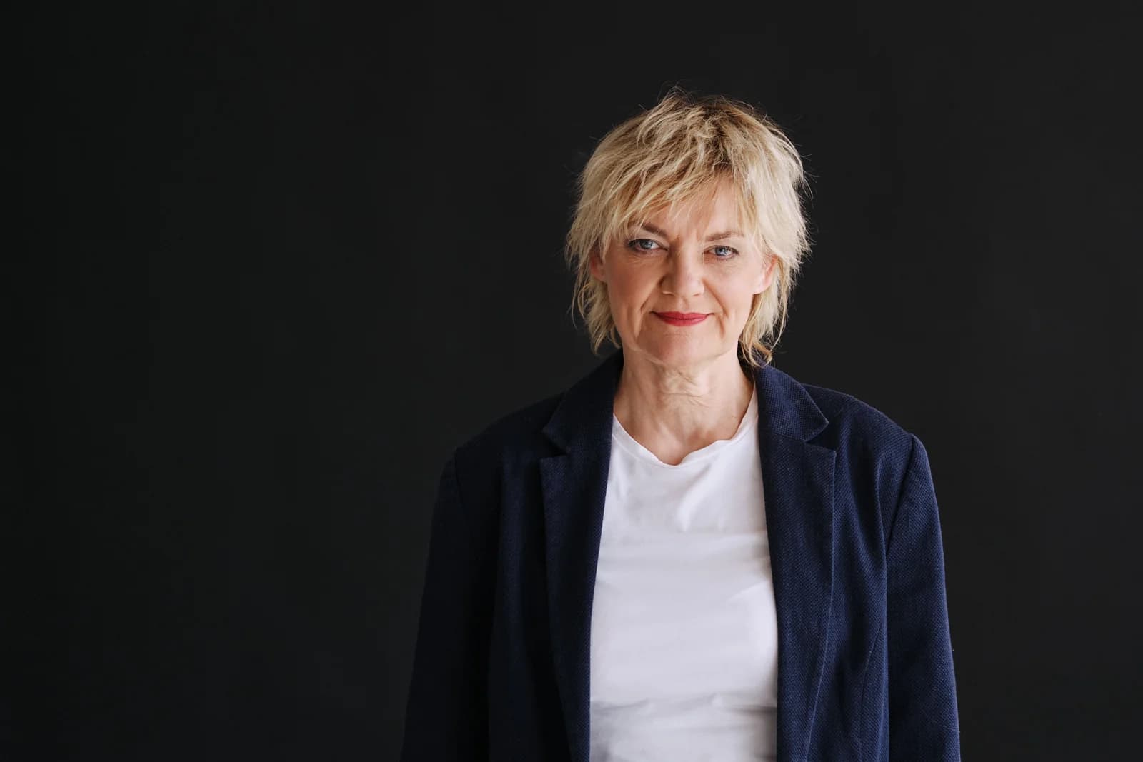 Anna Windmüller, Halbporträt im dunkelblauen Blazer vor schwarzem Hintergrund, ruhiger und souveräner Ausdruck
